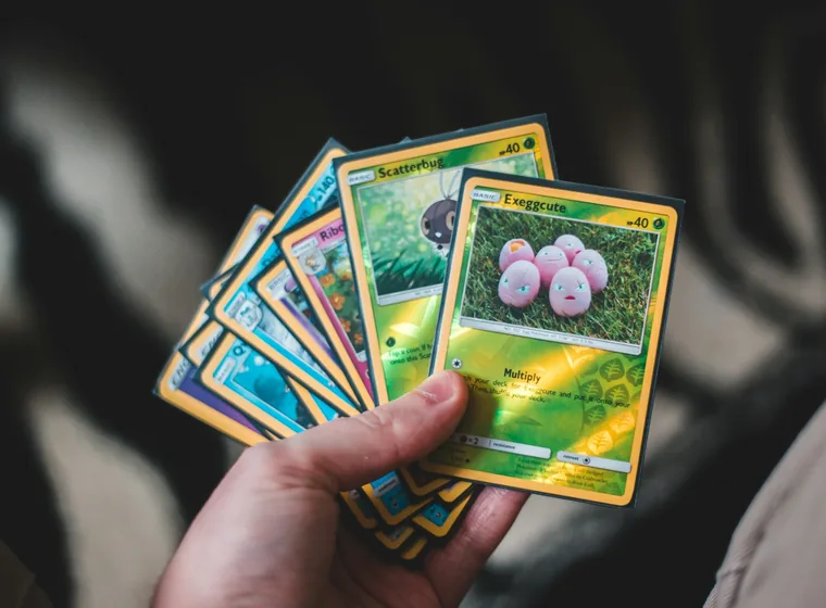 A hand holding a fan of Pok&eacute;mon trading cards