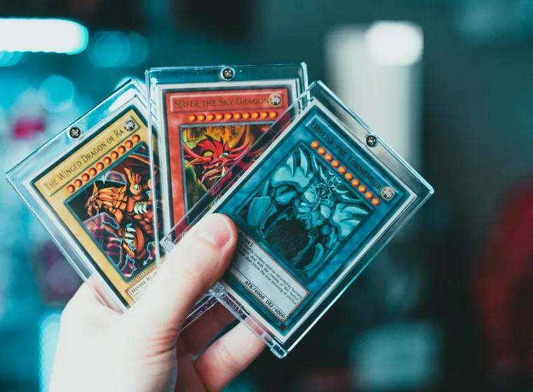 A hand holding three Yu-Gi-Oh! trading cards
