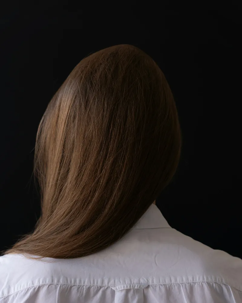 Long straight dark hair against a dark background