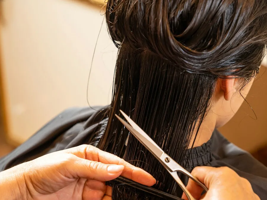 Stylist working through long sectioned hair during a weft install