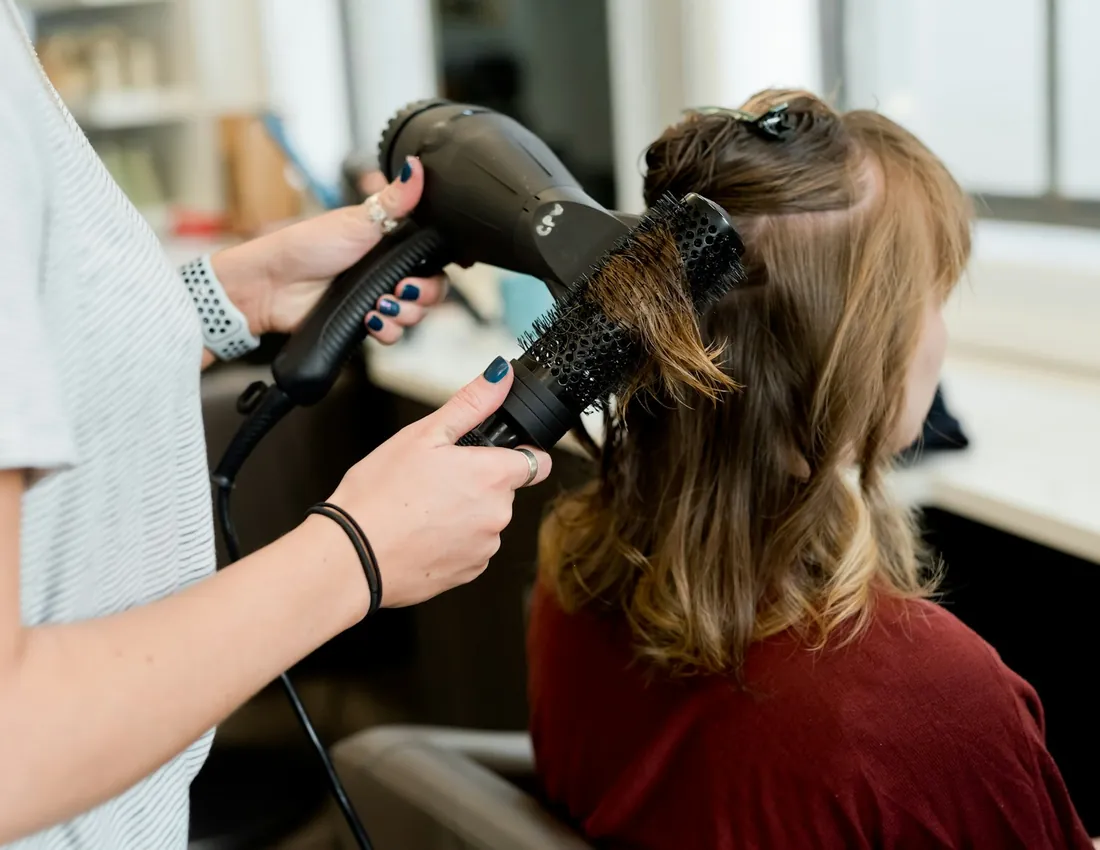 Stylists finishing a client's hair at a styling station