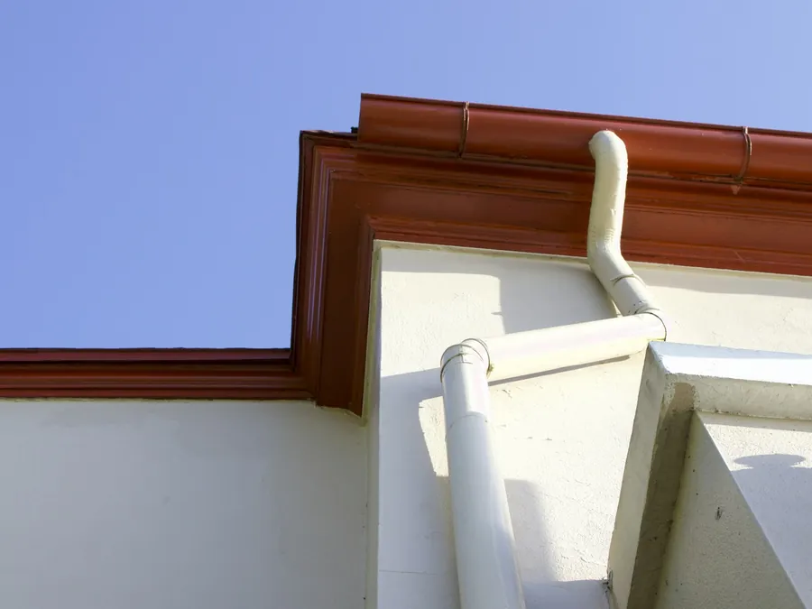 Clean seamless gutter and downspout against a blue sky