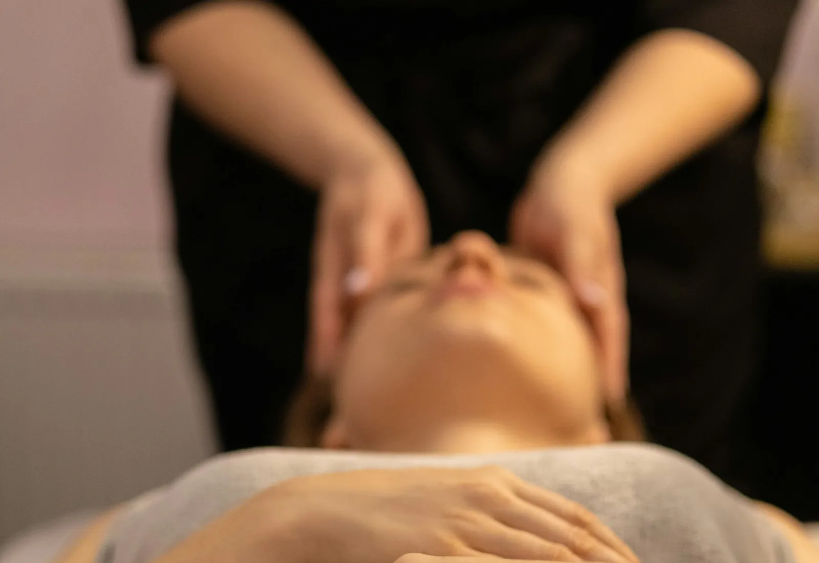 Esthetician performing a facial massage on a client lying on a treatment bed